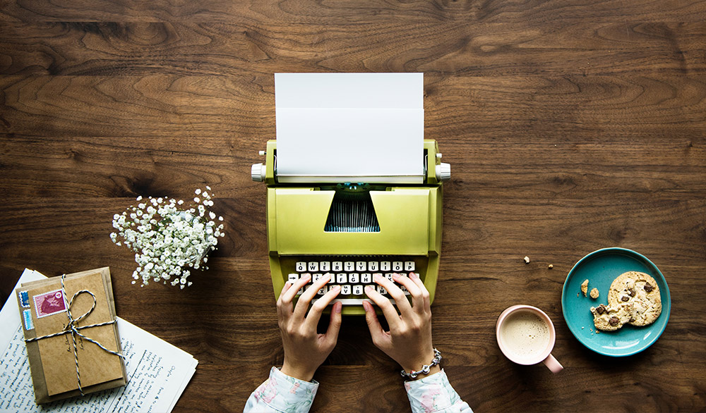 Someone typing on a green typewriter to become an author