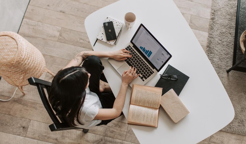 Person looking at Amazon sales analytics on a laptop with a book