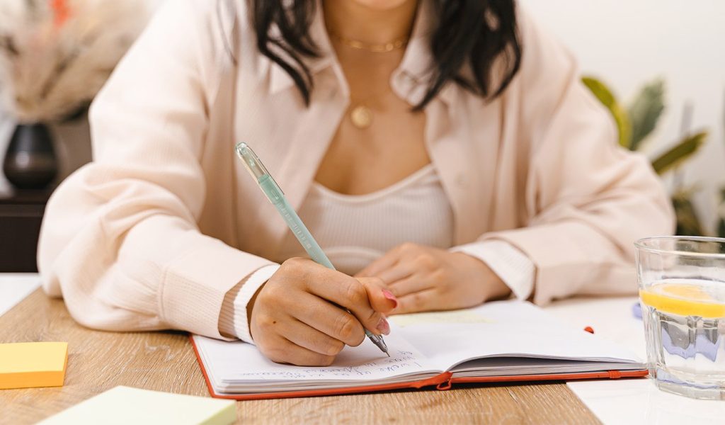 Person writing a book blurb draft down in a notebook