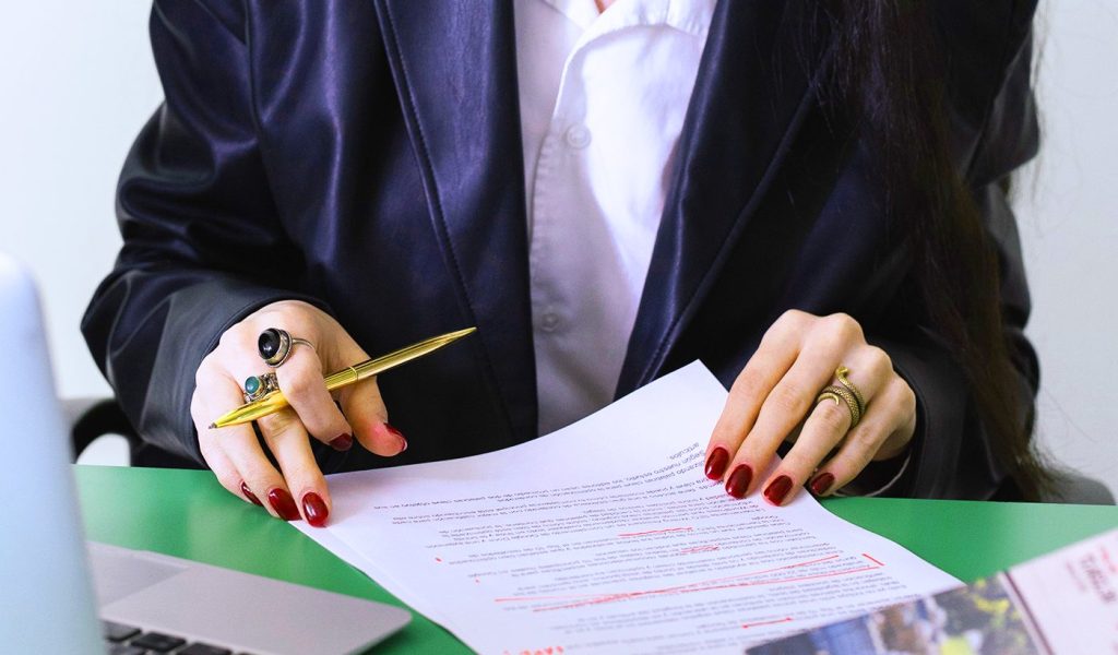 Person editing their book blurb with a pen and a printed piece of paper